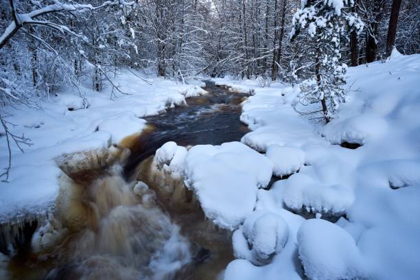 istock Winter landscape with river flowing through snowy forest, long exposure 1453433001