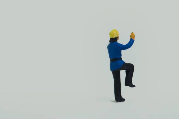 istock Miniature figure of a fireman standing on one leg on a white background 1453435337