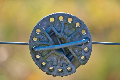 A close-up shot of an electric fence wire and rope tensioner