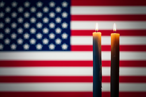 Mourning in the country united states of america. A burning candle on the background of the US flag. Victims of cataclysm or war concept. memorial day, remembrance day National mourning.
