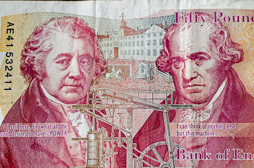Reverse of a used £50 banknote from the Bank of England showing the engineers and entrepreneurs Matthew Boulton and James Watt.  Used banknote, photographed at a slight angle.  Their historic factory in Soho, Birmingham is shown at the back with their Whitbread steam engine towards the bottom.