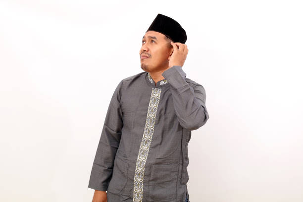 istock Thoughtful asian muslim man standing while holding his head and looking above. Isolated on white background 1453438590