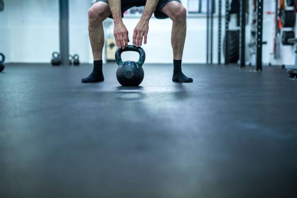 istock Low section of man lifting kettlebell in gym 1453441349