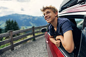 Teenage boy looking out of car parked by the road in high Austrian Alps