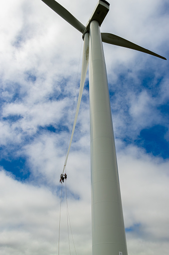 Two Rope access technicians abseiling down a wind turbine blade. Repairing the blade in N. Ireland