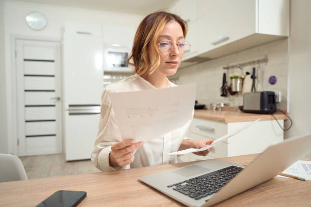 istock Calm focused female with documents seated at computer monitor 1453453841