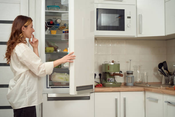 istock Female focused on selecting foodstuffs in her fridge 1453453918