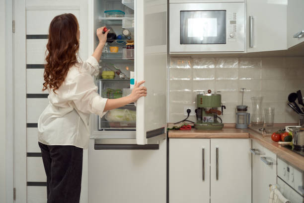 istock Woman taking beverage out of open fridge 1453453919
