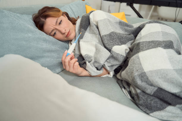 istock Ill female measuring her body temperature in bed 1453454010