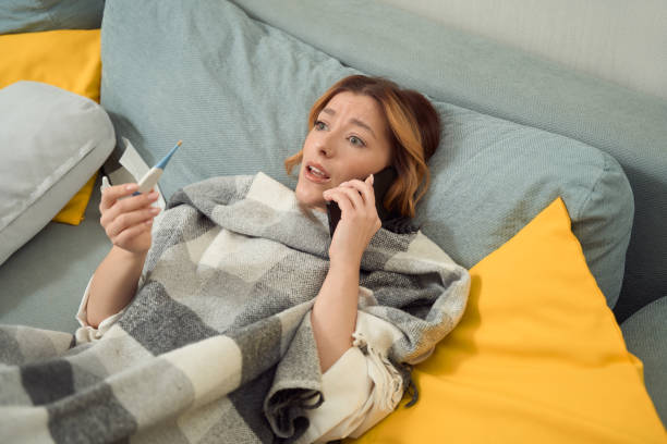 istock Sick woman talking on smartphone in bedroom 1453454023