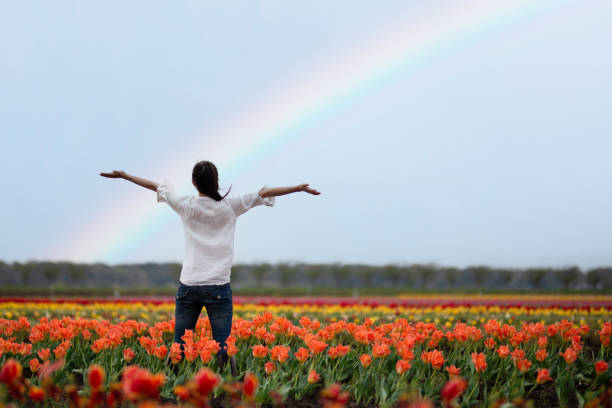 虹の花畑で両手を広げる女性