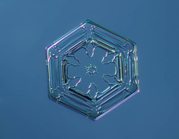Snowflake on smooth gradient background. Macro photo of real snow crystal on glass surface. This is small snowflake with unusual pattern.