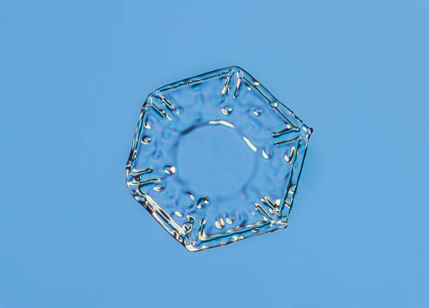 Snowflake on smooth gradient background. Macro photo of real snow crystal on glass surface. This is small snowflake with unusual pattern.