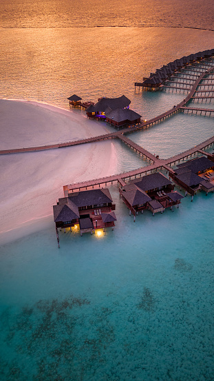 Maldives island resort in sunset with view over horizon drone view