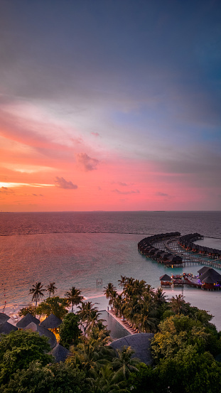 Maldives island resort in sunset with view over horizon drone view