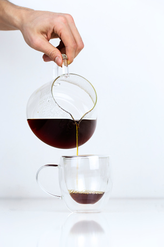 pouring filter coffee into mug on white table