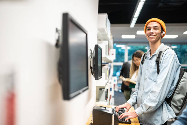 istock Portrait of a young student man searching a book on computer at library 1453463996