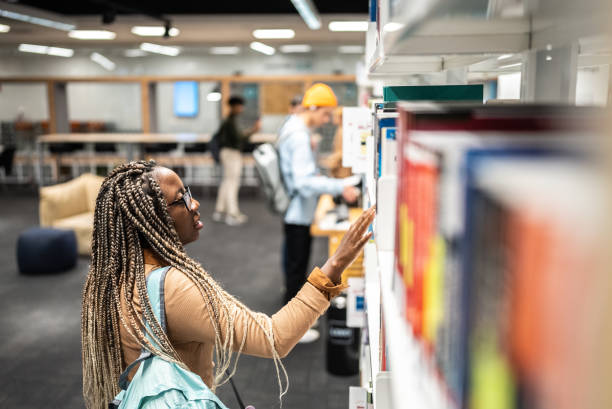 istock Young student woman choosing a book on a book stand at university library 1453464046