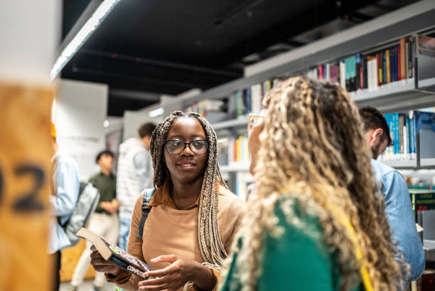 istock Young students women talking with her colleague at university library 1453464088