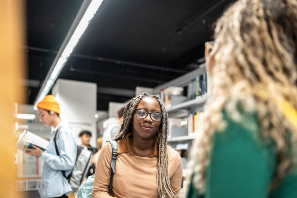 istock Young students women talking with her colleague at university library 1453464112