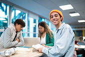 Portrait of a young student man while his friends talk in the background at university/school