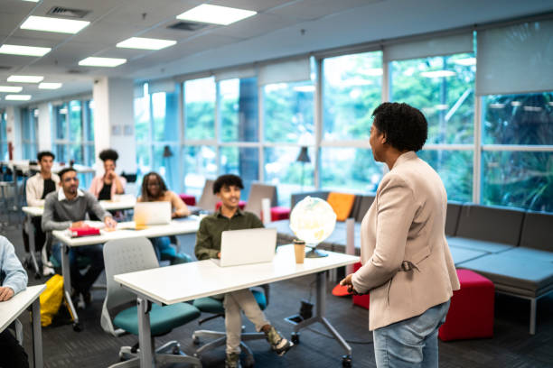 Mature teacher woman talking to students during class at university Mature teacher woman talking to students during class at university professor business classroom computer stock pictures, royalty-free photos & images