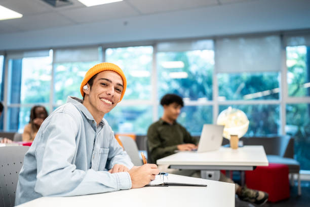 istock Portrait of a young university student man writing at university classroom 1453466391