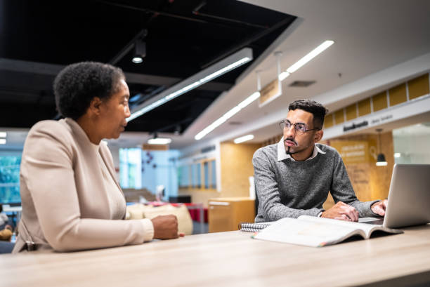 istock Teacher talking and giving assistance to university student at university 1453466523