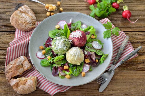Homemade traditional South Tyrolean dumpling trio, consisting of the three different kinds spinach, cheese and beetroot, on mixed leaf salad with croutons