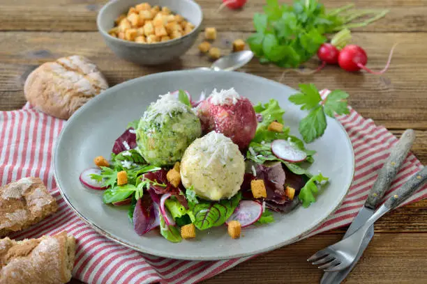 Homemade traditional South Tyrolean dumpling trio, consisting of the three different kinds spinach, cheese and beetroot, on mixed leaf salad with croutons