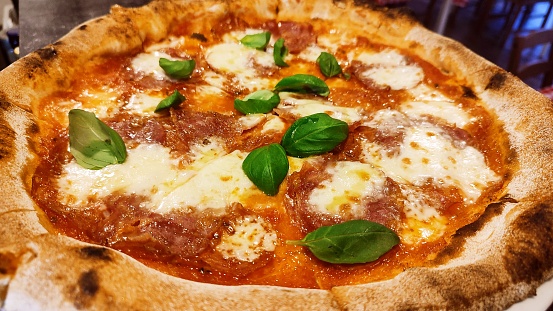Italian pizza with salami and basil