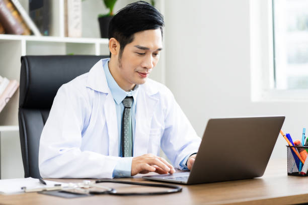 istock Asian male doctor portrait sitting at work 1453471567