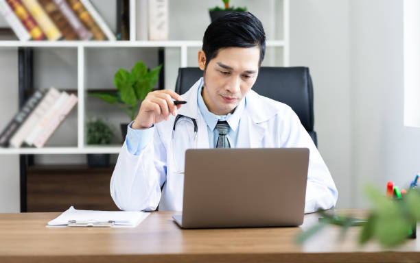 istock Asian male doctor portrait sitting at work 1453471649