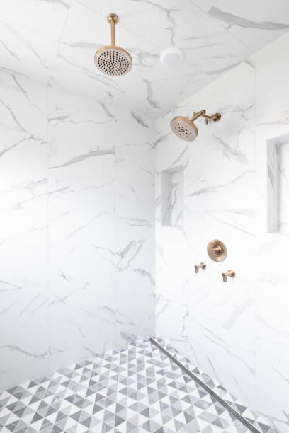 istock A large, marble tiled shower with gold shower heads. 1453472676