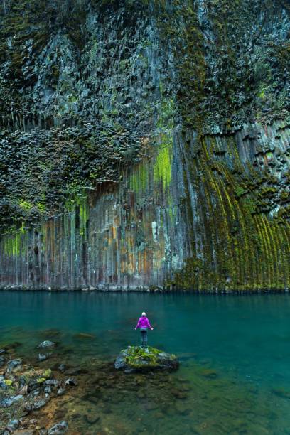 istock Person standing on a rock in front of a waterfall 1453476123
