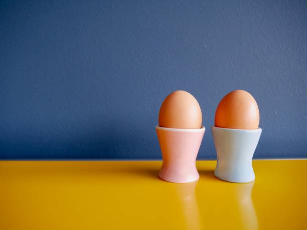 Blue and pink vintage pastel egg cup on yellow sideboard against blue background.