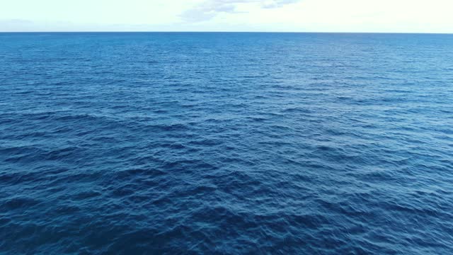Drone approaching calm blue ocean horizon of the open sea.
