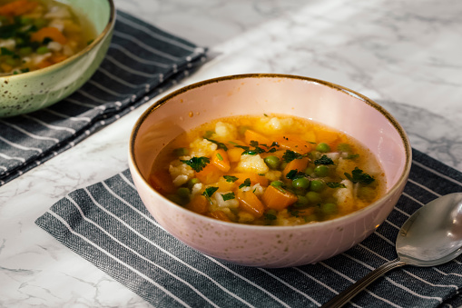 Vegetarian, vegan and gluten free stew with green peas, potatoes and vegetables. Served in a bowl with spoon on rustic and wooden table with copy space