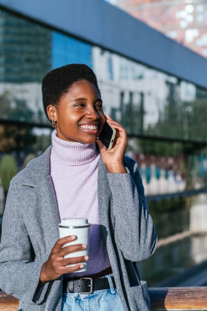 istock Cheerful black woman with coffee having smartphone conversation 1453487987