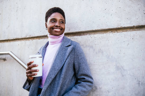 istock Black woman in coat leaning on concrete wall 1453487992