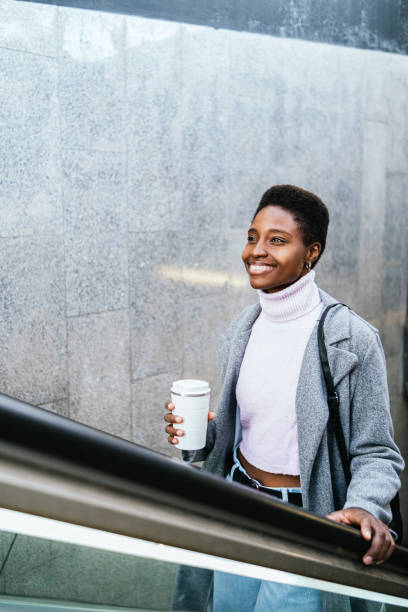istock Glad black female riding escalator from subway 1453488011