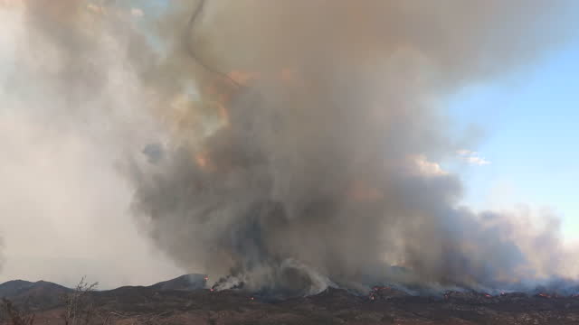 Black and grey smoke coming up from a wildfire burning on a mountain. Fairview Fire in Hemet, California, USA, September 2022