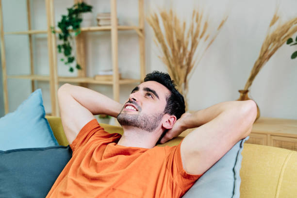 istock Cheerful man lying on sofa in living room 1453494655