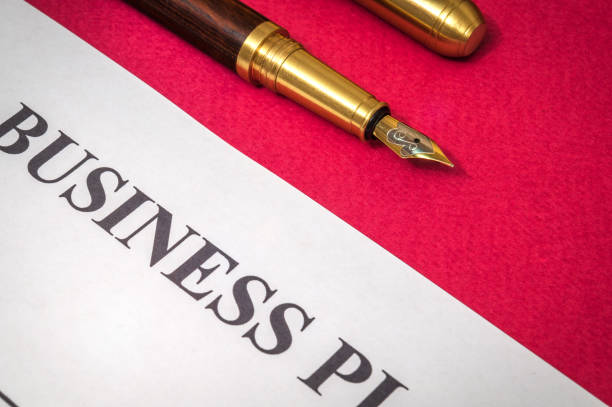 istock Office still life on red table with gilded pen a and business plan is preparing for the notes 1453495347