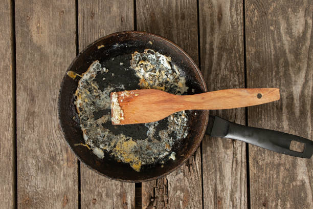 frying pan with food leftovers on a wooden table after breakfast in the kitchen stock photo