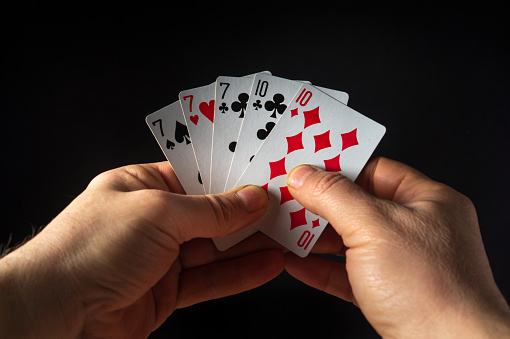 The player hands hold playing cards with a winning combination of full house or full boat. Success at poker