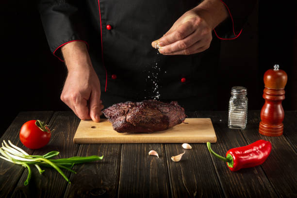 istock The chef sprinkles the baked beef meat with salt. Work environment on the kitchen table. Asian cuisine 1453500333