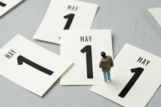 Young man figurine looking at calendar leaves. May 1 concept.