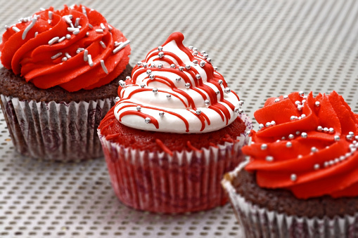 creamy cupcakes in shades of red on white background