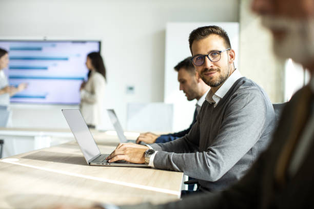 istock Cheerful businessman looking at camera while working on laptop 1453513775